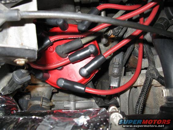 Red spark plug wires connected to a red distributor cap in an engine bay