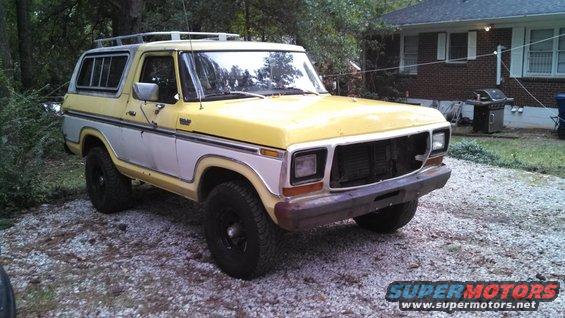 Yellow and silver 1978 Ford Bronco with a roof rack parked on gravel
