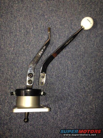 Chrome and black shifter assembly with a white shift knob on a blue carpeted surface