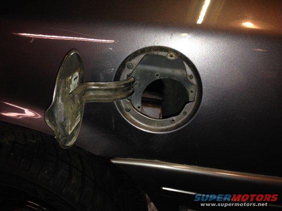 close-up of open fuel filler door on a dark-colored car