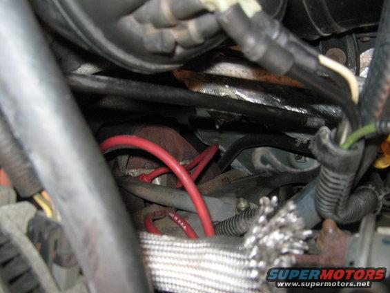 Engine bay showing red spark plug wires and various hoses and cables