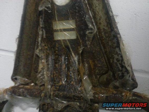 rusted metal bracket covered in plastic wrap, showing some corrosion and wear