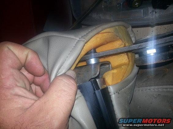 Hand pulling on beige seat upholstery near metal mechanism and foam padding
