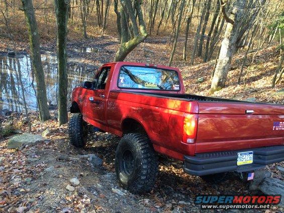 Red pickup truck with lifted suspension and off-road tires on a dirt path