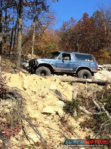 Blue SUV with off-road tires climbing a dirt embankment
