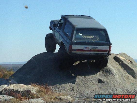 Ford Bronco climbing a rock face, rear view. License plate visible