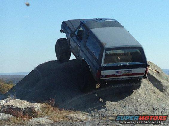 Blue SUV climbing a rock face, lifted suspension, off-road tires
