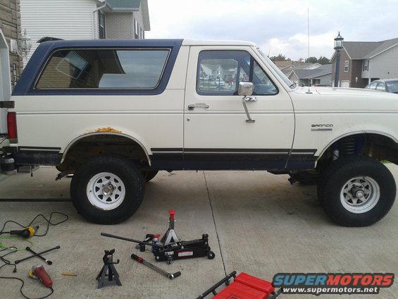 1988 Ford Bronco side view, jacked up with tools on the ground