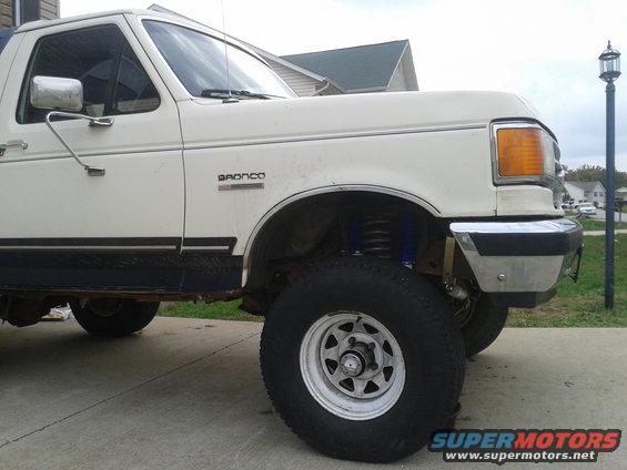 White Ford Bronco with blue shocks, parked on a driveway