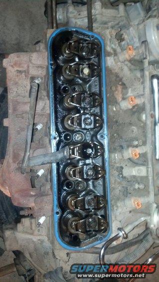 Engine valve cover removed showing rocker arms and valve train components