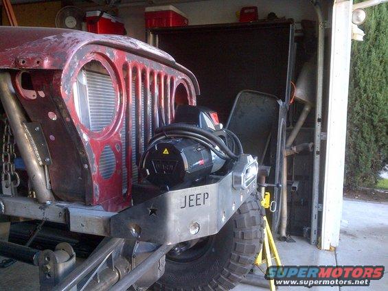 Jeep CJ-series front end with winch mounted on custom bumper. Red fender and grille are visible