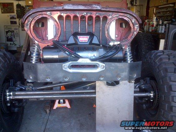 Front view of a Jeep CJ with a winch and custom bumper, showing the grille and headlights removed