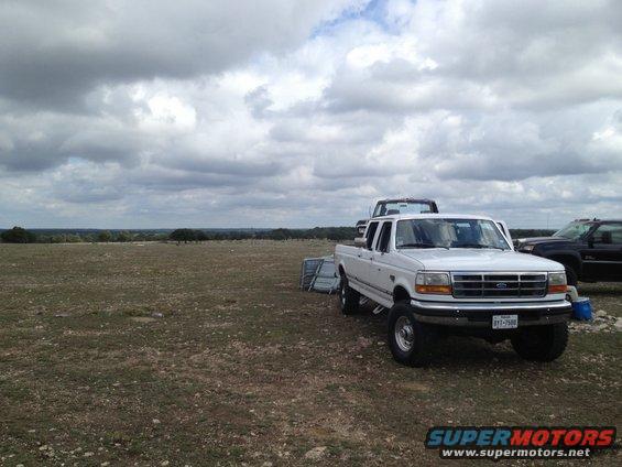 White 1997 Ford F-350 pickup truck parked in a dry, grassy field under a cloudy sky