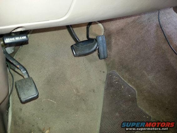 Driver's side footwell with brake and gas pedals visible. A lever labeled 'BRAKE RELEASE' is also present