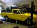 1963 Ford Ranchero - A yellow 1963 Ford Ranchero pickup truck is positioned on a vehicle lift inside a garage.