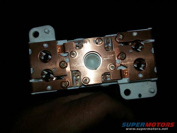 Close-up of a vehicle's electrical relay with copper contacts and white plastic housing