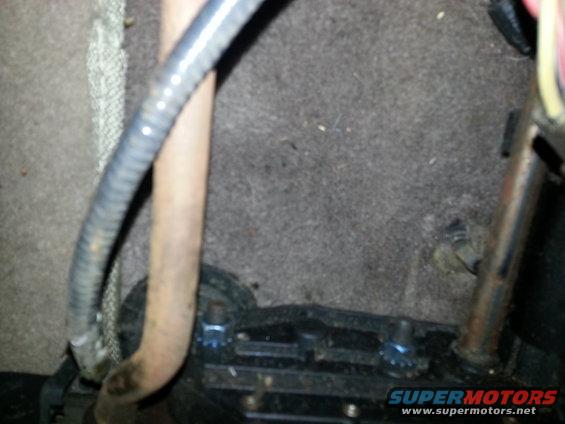 Interior floor with carpet, metal seat mounting bolts, and conduit