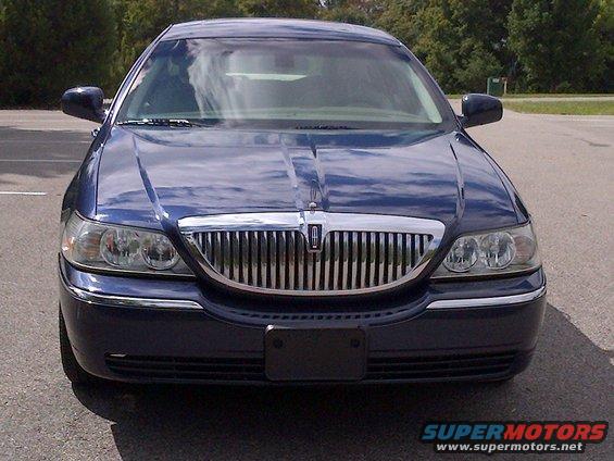 Dark blue Lincoln Town Car front view. Chrome grille with Lincoln emblem. Headlights visible