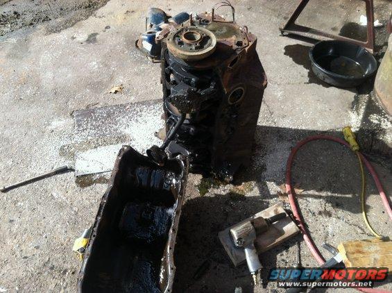 Engine block and detached oil pan on concrete with tools