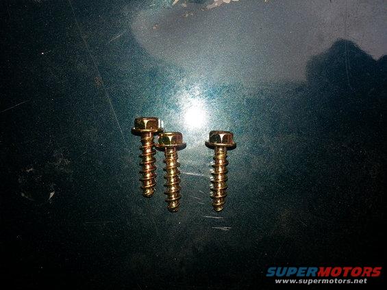 Three gold screws on dark green surface. Supermotors.net logo visible