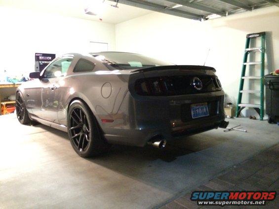 Gray 2013 Ford Mustang parked in a garage, rear 3/4 view. Black spoiler and wheels