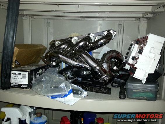 Chrome exhaust headers piled on a shelf with boxes