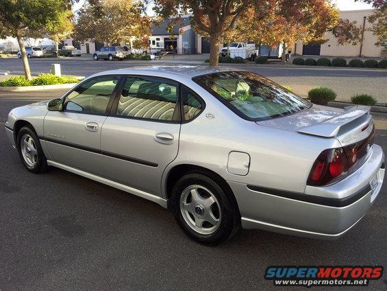 Silver 2001 Chevrolet Impala sedan parked on asphalt, rear three-quarter view