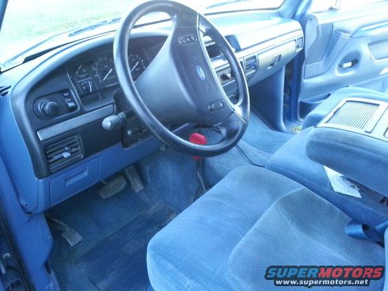 Blue fabric interior of a truck, showing dashboard, steering wheel, and seats. Watermark visible