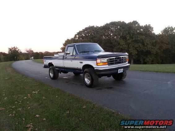 Blue and white Ford F-Series pickup truck on a paved road