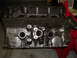 1967 Ford Mustang - A dark, cast iron engine block rests on a red engine stand, showing its internal structure.