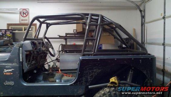 Jeep Wrangler interior showing dashboard, steering wheel, and custom roll cage. "WRANGLER 4.0L SPORT" decal visible