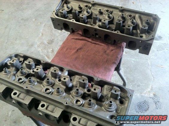 Two cast iron engine cylinder heads resting on a red cloth