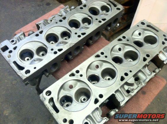 Two aluminum engine cylinder heads on a red cloth