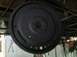 1978 Ford Bronco - A black flywheel with a toothed outer edge is suspended from the ceiling in a workshop.