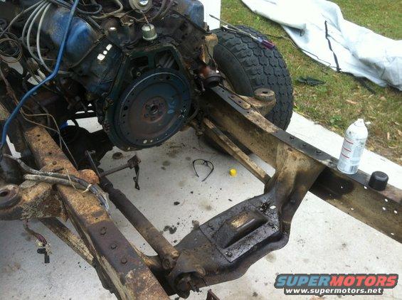 Vehicle frame with engine partially installed, showing suspension and drivetrain components