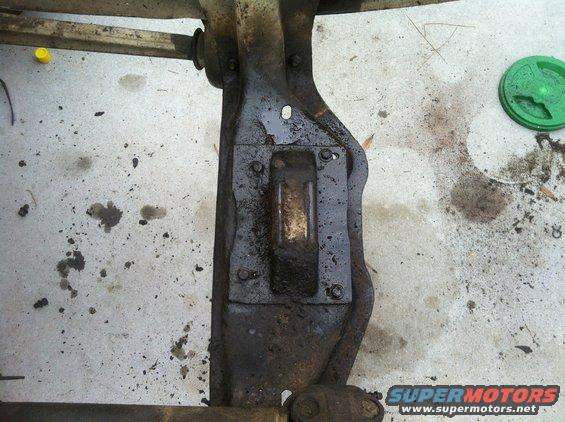 Vehicle frame component with bolts and grease stains on concrete