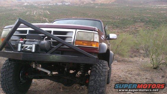 1996 Ford Bronco with aftermarket winch and brush guard, parked on a dirt road in a desert landscape