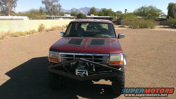 Red pickup truck with custom front bumper, winch, and hood scoops
