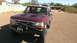 1996 Ford Bronco - A red Ford Bronco sits in a dry, outdoor lot under a clear sky.