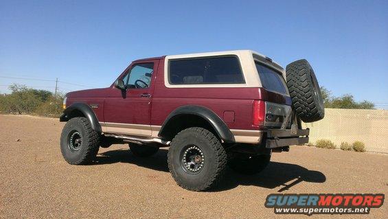 Maroon and tan 1996 Ford Bronco with large tires and rear-mounted spare tire