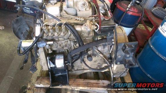 Diesel engine assembly mounted on wooden pallet, with fuel lines and wiring visible