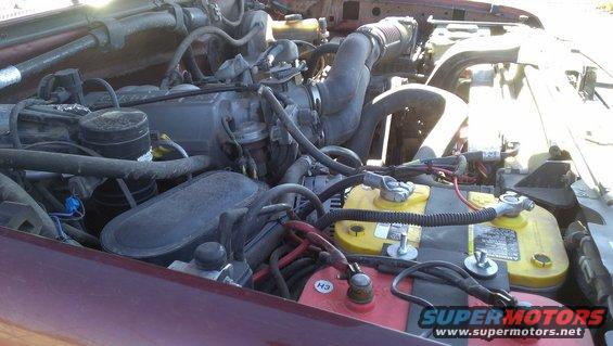 Engine bay showing a V8 engine, dual yellow top batteries, and red top battery