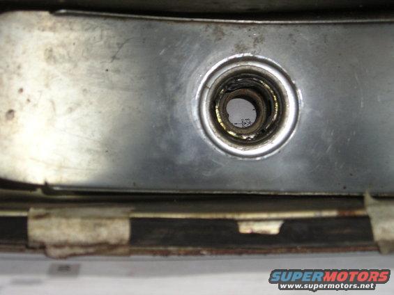 close-up of a metal bracket with a circular opening showing some internal components and text underneath