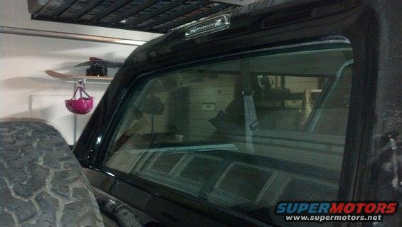 Black SUV rear window and tire in garage. Snowboard and helmet on shelf