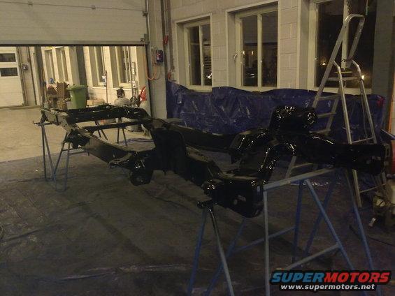 Black painted vehicle chassis on stands in a garage