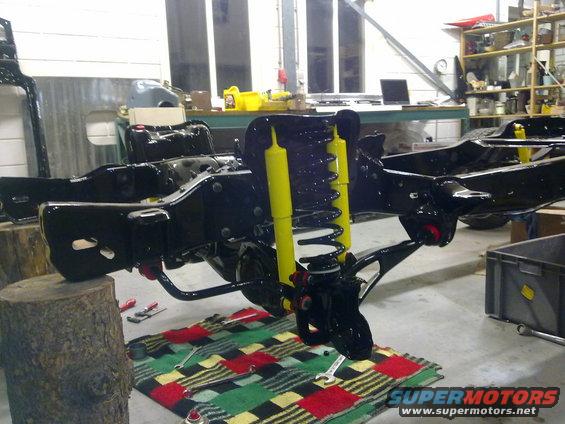 vehicle frame with yellow shocks and springs, tools on a blanket