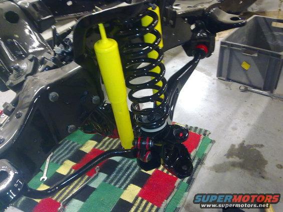 Front suspension part with yellow shock absorber and black coil spring