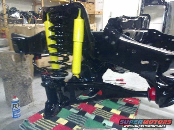 Black painted front suspension assembly with yellow shocks and black springs. A can of spray lubricant is on the left