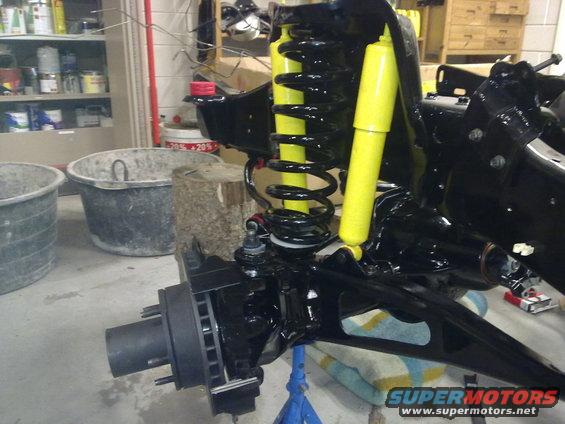 close-up of black suspension with yellow shocks and brake rotor