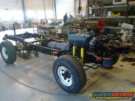 Vehicle chassis with engine and suspension components installed, in a workshop